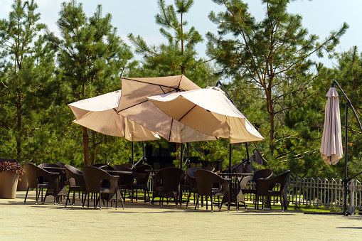 Street restaurant with umbrellas from the sun without people against the background of the forest