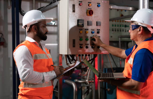 istock Engineer of a mechanical plant Inspecting and explaining the maintenance of the control panel to the mechanic 1415415473