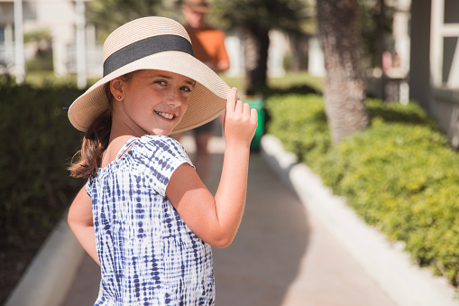 Teenage girl with a sun hat on walking in a park