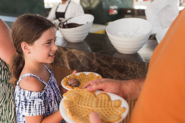 Child having waffles outdoors with a parent