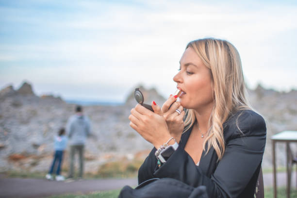 istock Young woman corrects her makeup while sitting in an outdoor cafe 1415421871