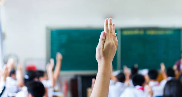 vista posteriore delle mani alzate nell'aula della scuola media - arto umano foto e immagini stock