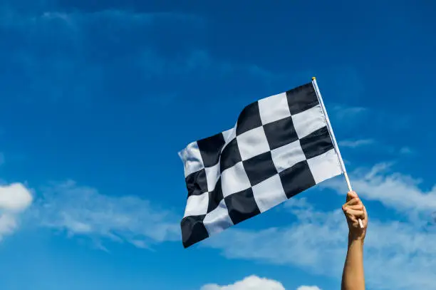 Hand holding checkered race flag in the air