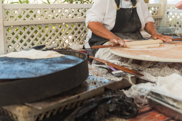 Woman using a rolling pin to flatten dough on a table