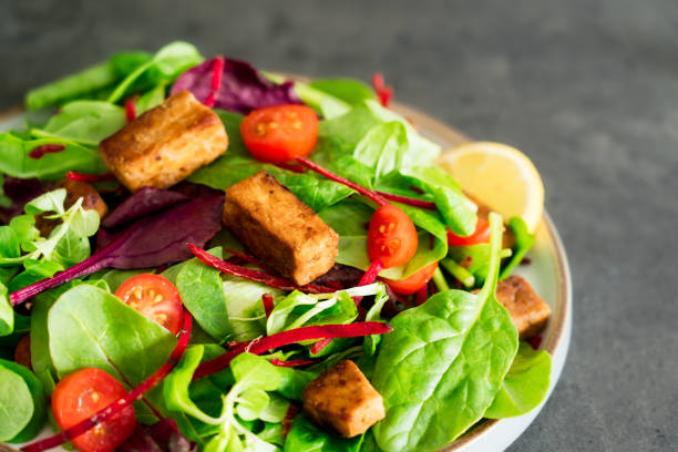 istock Healthy salad with roasted tempeh, fresh cherry tomatos, beetroot straws, spinash and lettuce leaves on plate. Tempeh is fermented soy bean. Plant based protein. Healthy Cooking and eating. Go vegan 1415430469