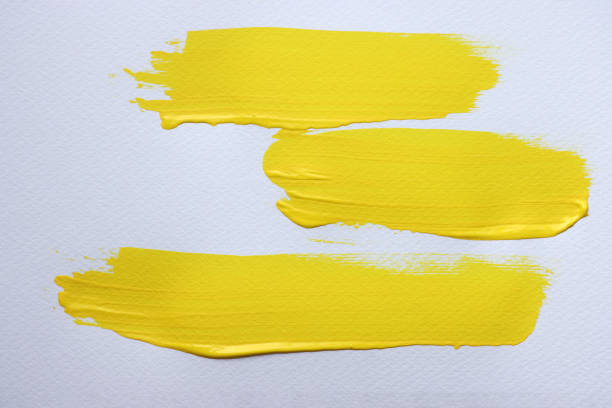 Three tubes of yellow acrylic paint in different colors with unscrewed caps and flowing paint, spread on the table. Close-up. Selective focus.