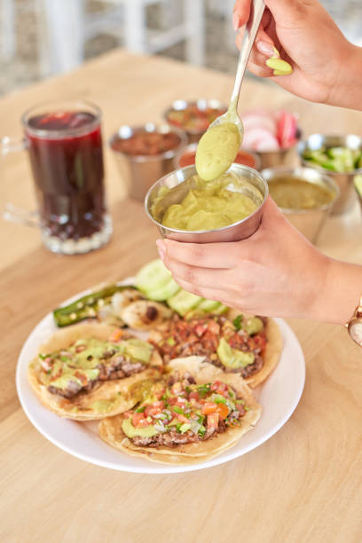 istock Girl adding salsa to her delicious tacos 1415431621