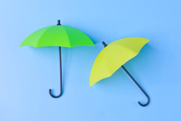 istock Green and yellow umbrella isolated on a blue background 1415434903