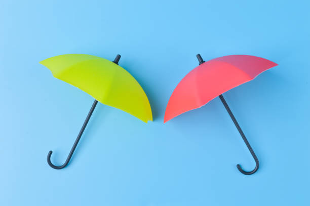 istock Yellow and red umbrella isolated on a blue background 1415434916