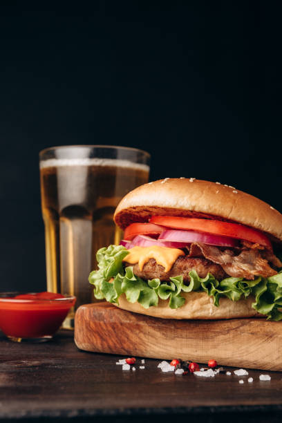 istock Burger hamburger with crispy bacon and potatoes fries on a dark background 1415435181