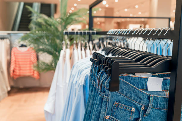 ropa y jeans en perchas en una tienda de cerca - shirt hanger hanging blue fotografías e imágenes de stock