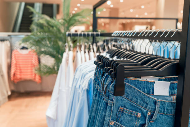 clothing and jeans on hangers in a store close up - merchandise multi colored arrangement blue imagens e fotografias de stock