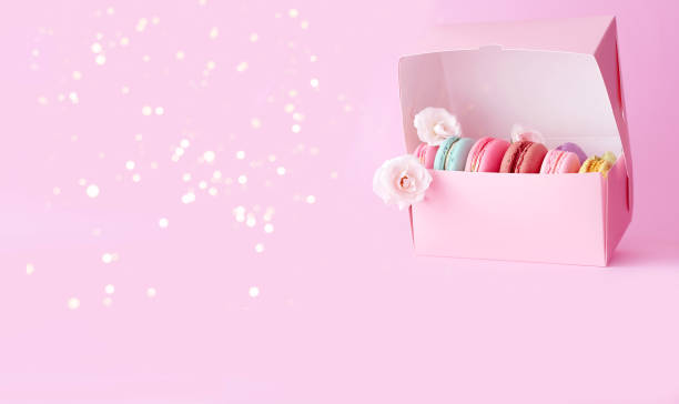 istock Gift box with colored macaroons on pink background with white roses. 1415438568