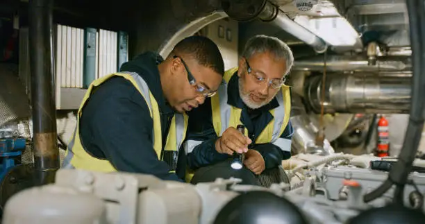 Photo of Mature engineers working to repair a machine with mechanical tools and equipment together. Professional industry workers doing quality control checks on systems. Skilled coworkers doing maintenance.