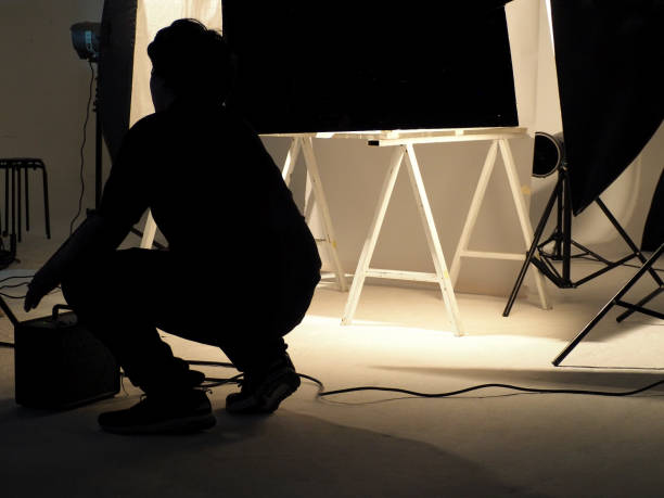 istock Silhouette of people working in production studio for shooting or recording by digital camera and lighting set. 1415441009