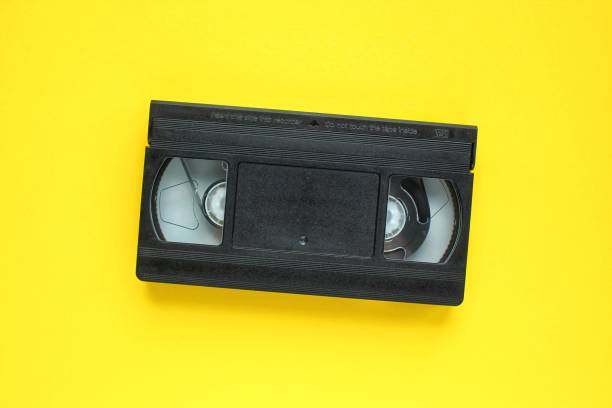 istock Black VHS videotape recorder cassette on yellow background 1415441067