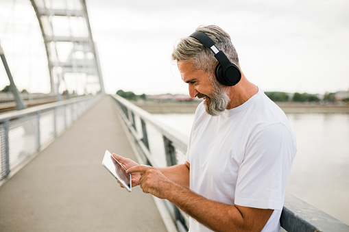 Smiling sporty man with headphones and digital tablet having workout