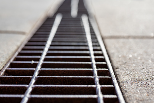 Grate over a stormwater trench in a concrete slab. . High quality photo