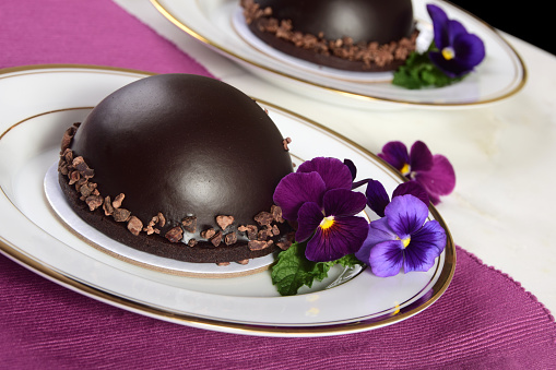 Individual, indulgent and romantic dark chocolate cake bomb filled with chocolate mousse and garnished with fresh flowers and mint.