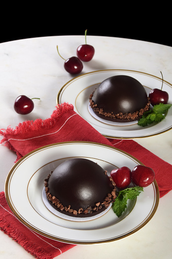 Individual, indulgent and romantic dark chocolate cake bomb filled with chocolate mousse and garnished with cherries and mint.