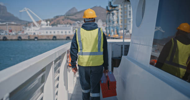 istock Industrial logistics construction port worker walking on ship out looking the ocean. Man wearing safety uniform carrying toolbox, working on freight boat at sea about to do maintenance repair 1415444653
