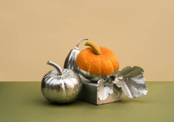 Modern still life with various pumpkins decorated in silver on a podium made of bricks