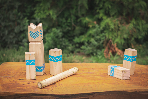 Kubb wooden figures on the wooden bench in park