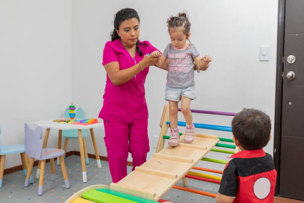 un pédiatre aide une fille à se promener dans un jeu en bois, tandis qu’un garçon les regarde - doctor domestic room cabinet cabinet member photos et images de collection