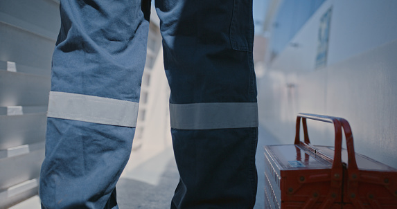 Handyman, plumber or mechanic standing with his toolbox and wearing uniform. Closeup legs of a technician or contractor ready to fix or do maintenance and repair work. Contact us for repairman work