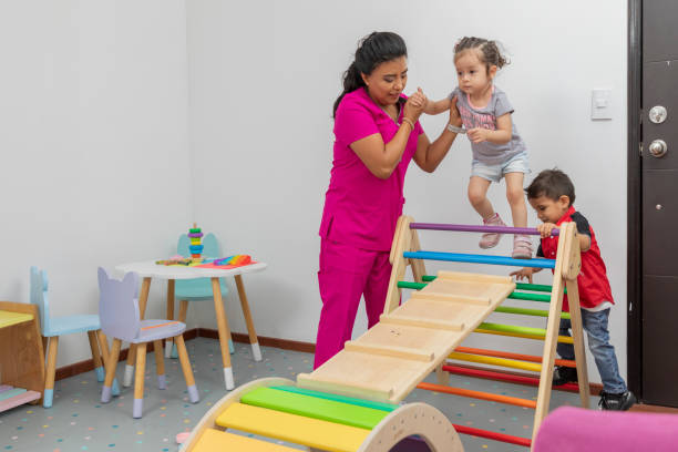 médecin pédiatre jouant avec un garçon et une fille, dans la salle de jeux de son bureau - doctor domestic room cabinet cabinet member photos et images de collection