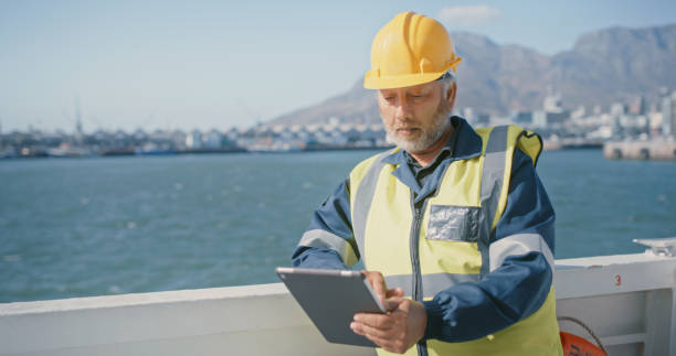 istock Marine chief engineer working on a tablet while on ship at sea with ocean, blue sky copy space background. Senior supervisor using shipment app or software mangement with internet connection on boat 1415450037