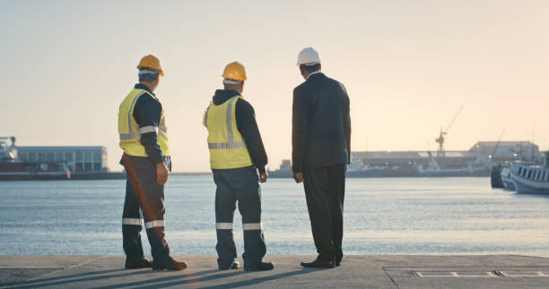 Logistics, inspecting and planning group of businessmen, engineer and construction worker site seeing at the port. Executive and quality control officer at docks for international shipping business.