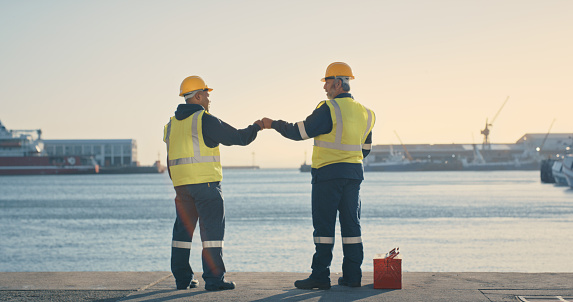 Logistics, delivery and shipping engineers looking motivated and ready with fist bump to build vision for ocean or sea cargo dock. Excited mechanical technicians with? idea for import and export port