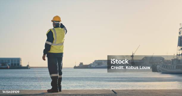 Shipping Freight And Logistics With A Supervisor Standing On The Dock In A Harbor Looking At The View And Waiting For A Delivery Or Shipment Safety And Control In The Import And Export Industry Stock Photo - Download Image Now