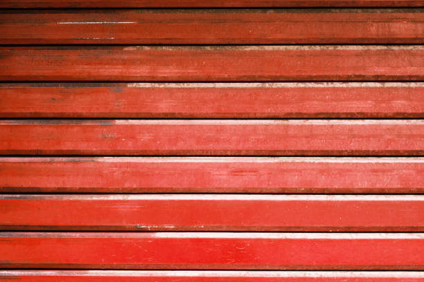 istock Red metal automatic garage shutter closeup, steel striped sliding door,  texture and pattern, old and weathered surface, dirty grunge background. 1415461318