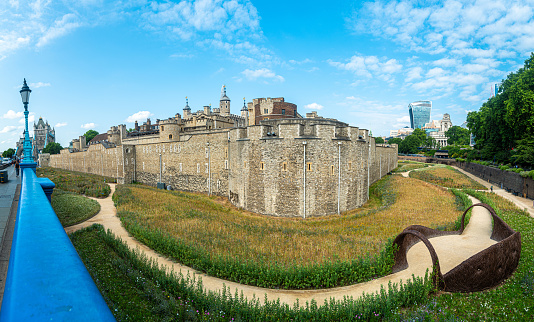 Panoramic view of the Tower of London with outer wall and moat, Tower Bridge and Skygarden in the background