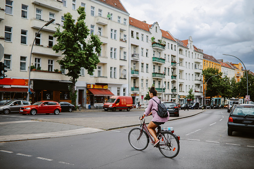 Commuter or a tourist woman on the bicycle in Berlin district of Kreuzberg, riding through the traffic.