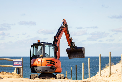Excavator working and repairing beach after storm, Cronulla, NSW Australia, background with copy space, full frame horizontal composition