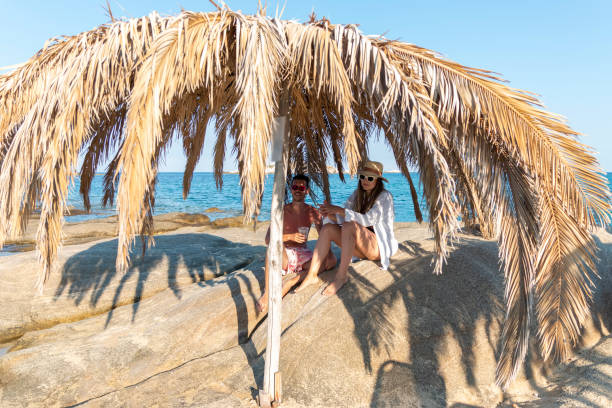 istock Young happy fun couple sitting on the beach 1415470213