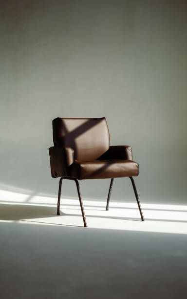 istock Stylish leather armchair in sunlight over white wall background. 1415471831