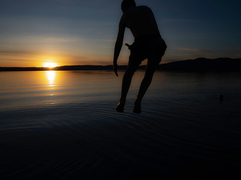 Silhouette of person jumping into water