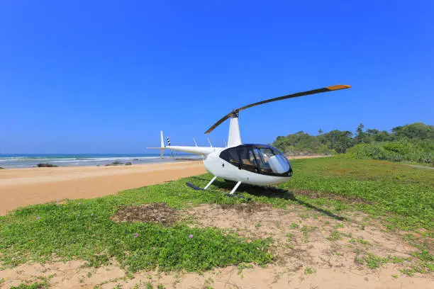 White helicopter Robinson R44 landed on the beach