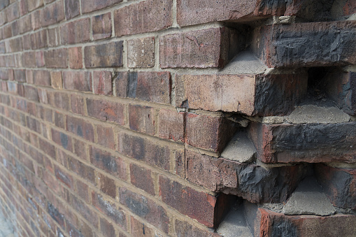 Close up of a striking corner joint of a uniformly laid brick wall with colored red ashlar bricks to use as background synonym for wall, brick and joints