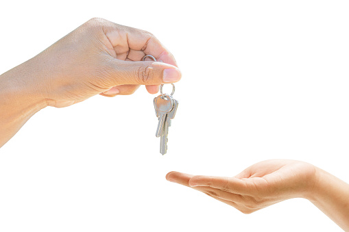 Close up holding house key giving other in hand. on white background, Mortgage loan approval home loan, and insurance concept.