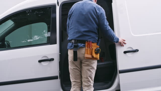 Handyman, repairman or builder services arriving in a van in a neighborhood to fix or do home improvement. A contractor walking in a suburb ready to do renovations, building and repairs
