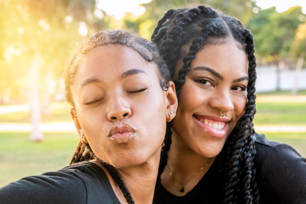 jeunes femmes lesbiennes souriantes posant en regardant la caméra - couple black american culture kissing photos et images de collection