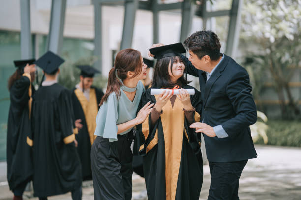 誇り高いアジアの中国人の両親と娘が大学の卒業ガウンを着て大学の建物の外で - scroll content ストックフォトと画像