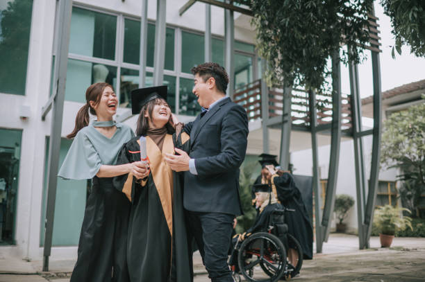 誇り高いアジアの中国人の両親と娘が大学の卒業ガウンを着て大学の建物の外で - scroll content ストックフォトと画像