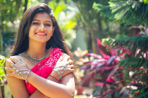 portrait of attractive indian female model in vacation on paradise tropical beach by ocean sea. hindu woman with kundan jewelry set traditional India costume red wedding sari.asian girl sensual look