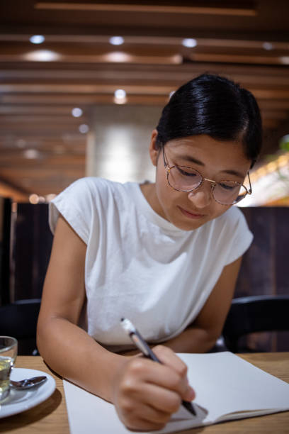 istock Young woman writing something on notebook in cafe 1415485054